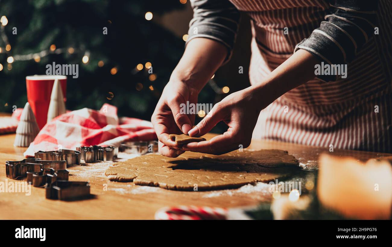 Joyeux Noël, Bonne Année.Biscuits au pain d'épice cuisson, cuisson au four.La jeune femme sculpte, coupe et porte des figurines de biscuit de pain d'épice à partir de pâte à pétrir en utilisant des formes spéciales de cuisine.Photo de haute qualité Banque D'Images