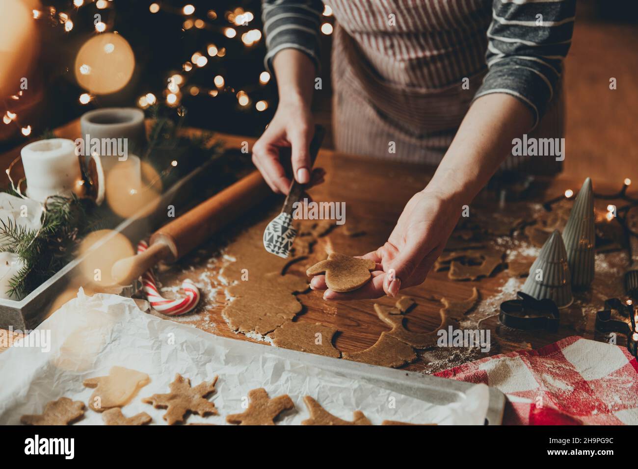 Joyeux Noël, Bonne Année.Biscuits au pain d'épice cuisson, cuisson au four.La jeune femme sculpte, coupe et porte des figurines de biscuit de pain d'épice à partir de pâte à pétrir en utilisant des formes spéciales de cuisine.Photo de haute qualité Banque D'Images