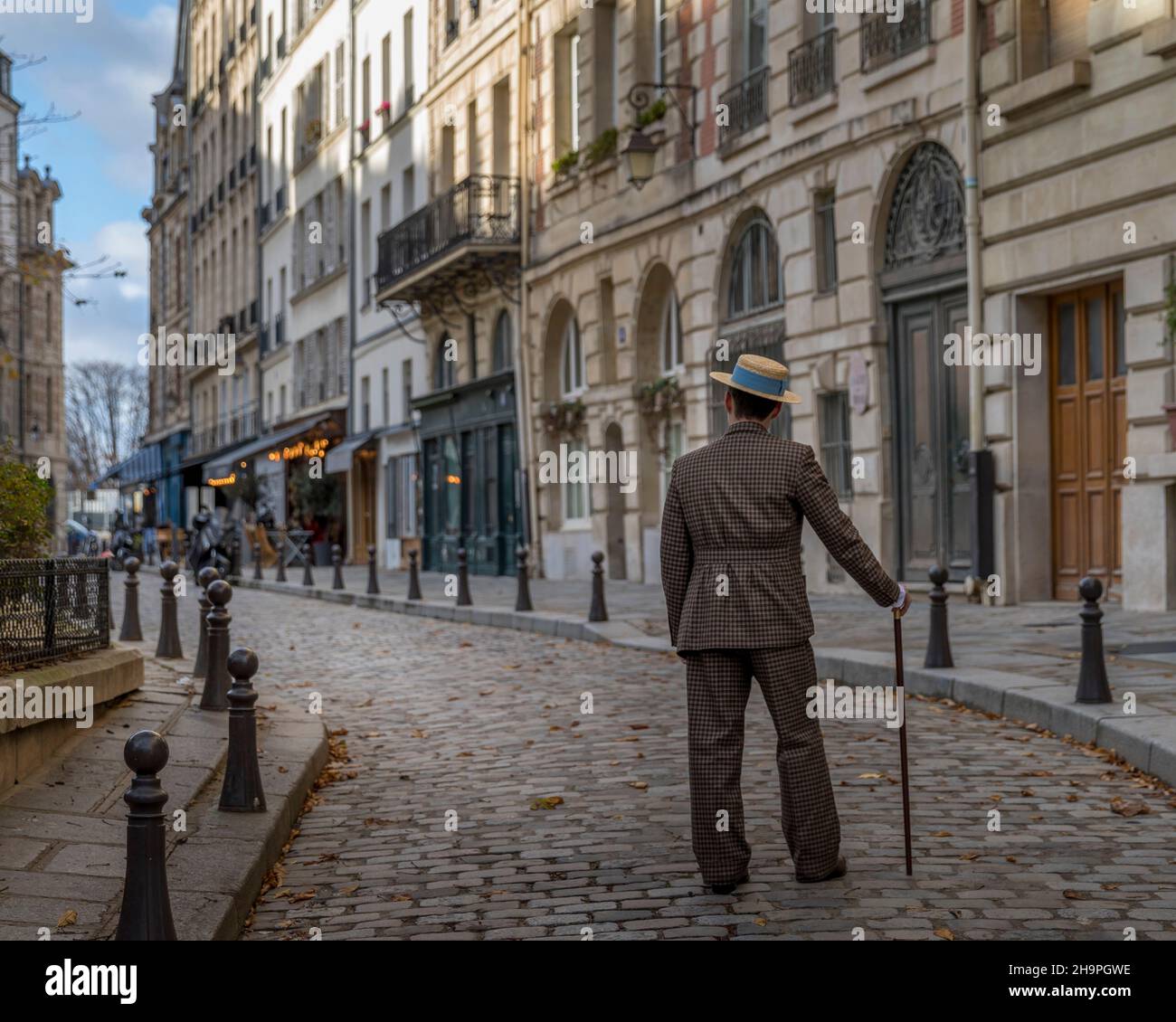 Paris, France - 28 novembre 2021 : un homme au chapeau, habillé au début du siècle, marche dans les rues de Paris Banque D'Images