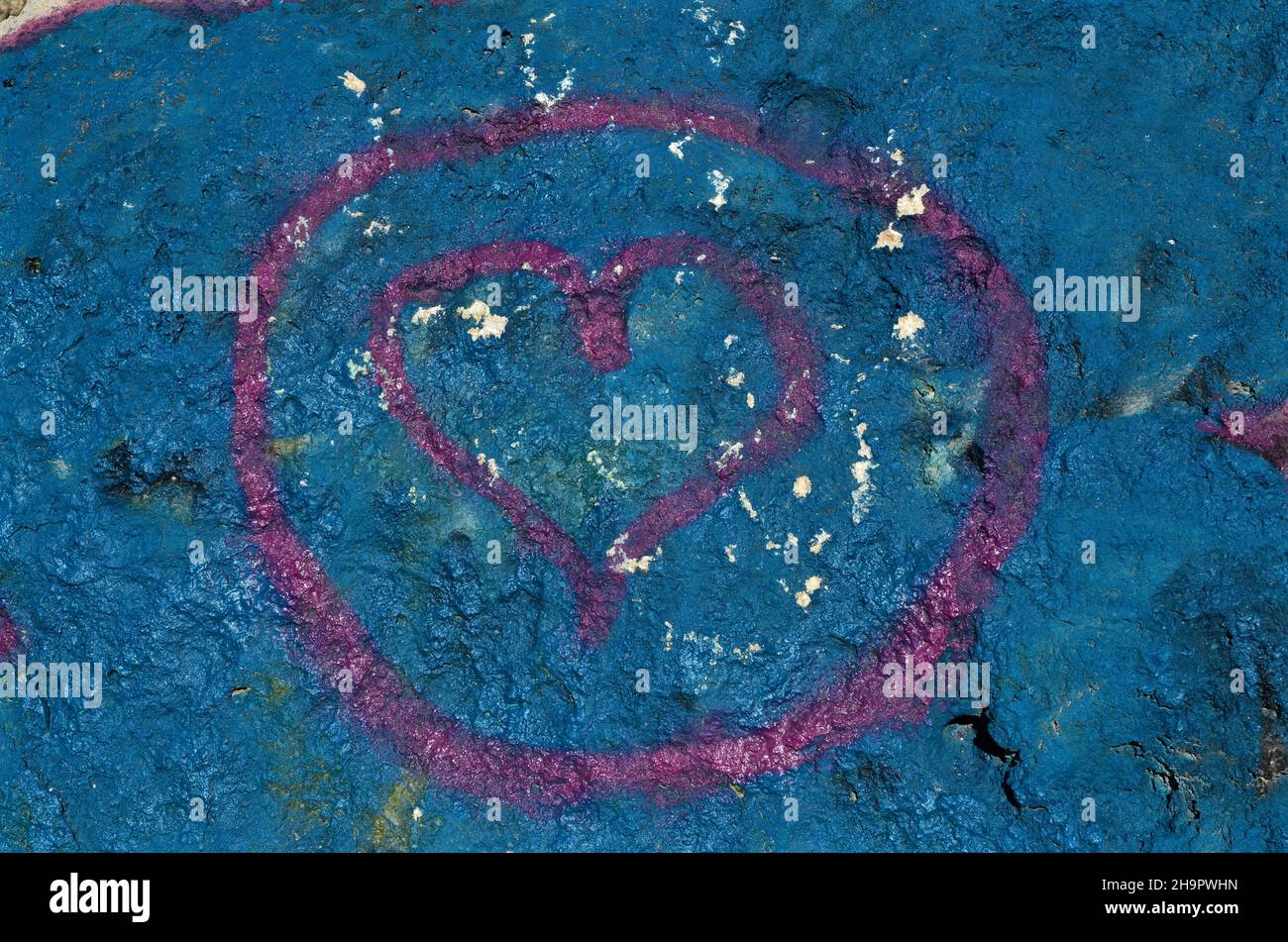 Coeur peint comme symbole @ peint sur le mur bleu, coeur rose dans le cercle sur le mur bleu, forme de coeur, symbole de l'amour, signe de l'amour, symbole de l'amour,preuve de Banque D'Images
