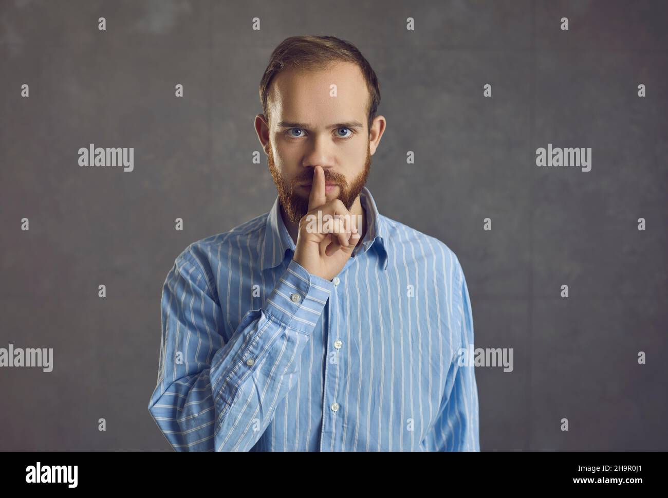 Homme caucasien adulte montrant shh geste tenant le doigt sur les lèvres portrait de studio Banque D'Images