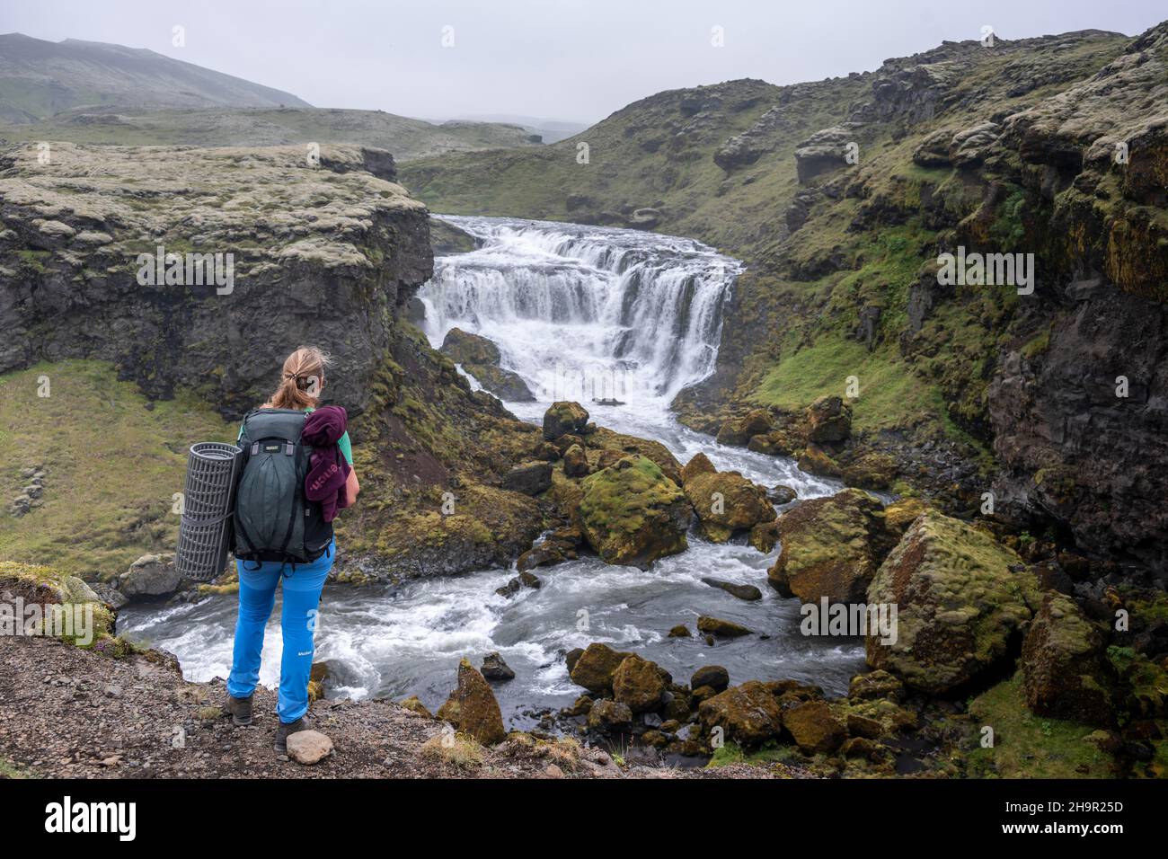 Randonneur avec grand sac à dos de randonnée en face de la cascade, paysage au sentier de randonnée de Fimmvoerouhal, Islande du Sud, Islande Banque D'Images