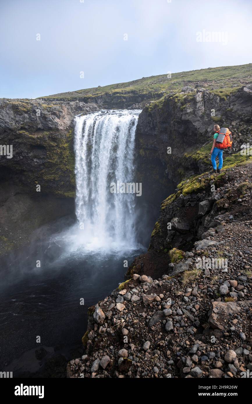 Randonneur avec grand sac à dos de randonnée en face de la cascade, paysage au sentier de randonnée de Fimmvoerouhal, Islande du Sud, Islande Banque D'Images