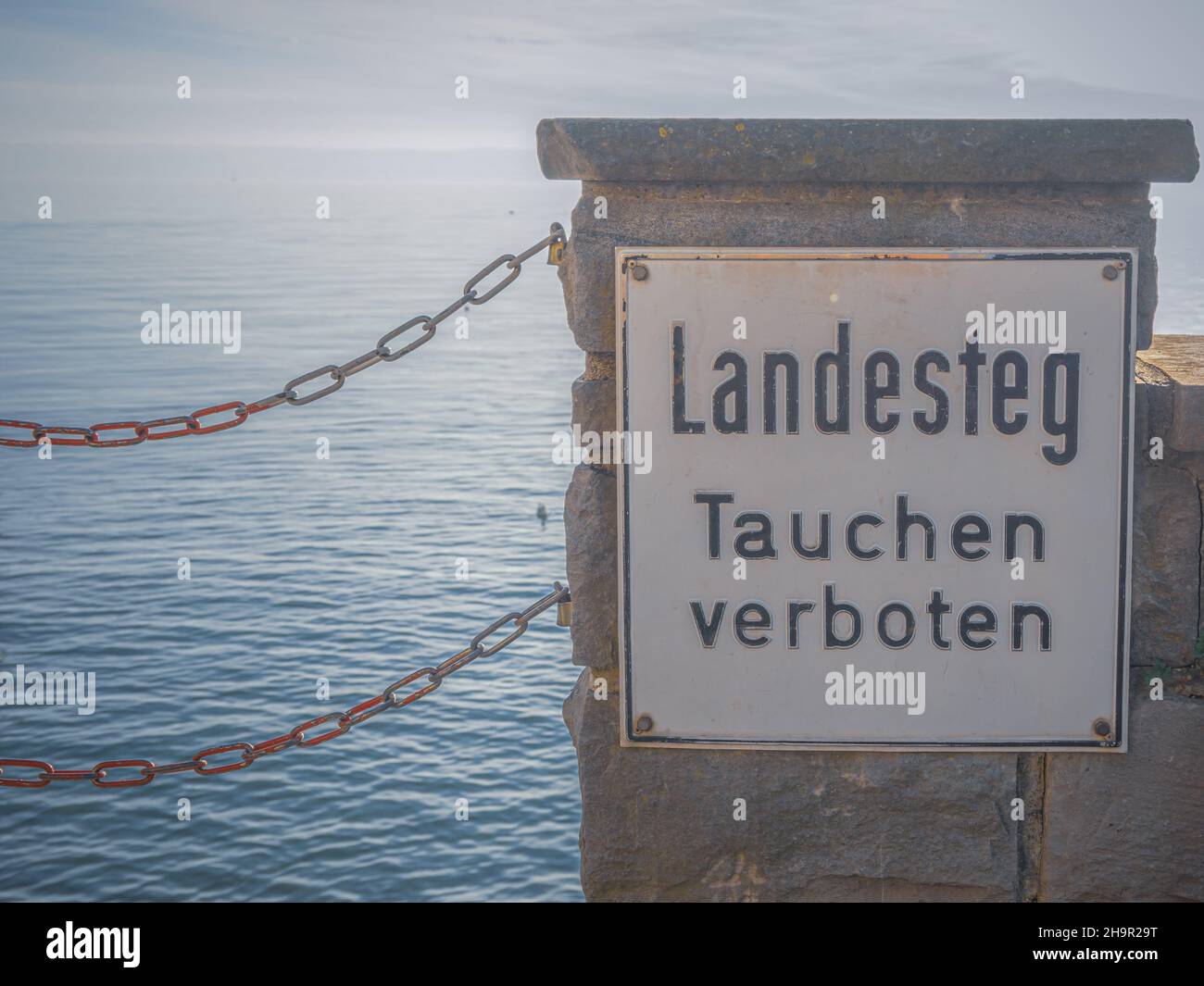 Panneau d'interdiction allemand sur un mur de front de mer: Landesteg - Tauchen verboten. Banque D'Images