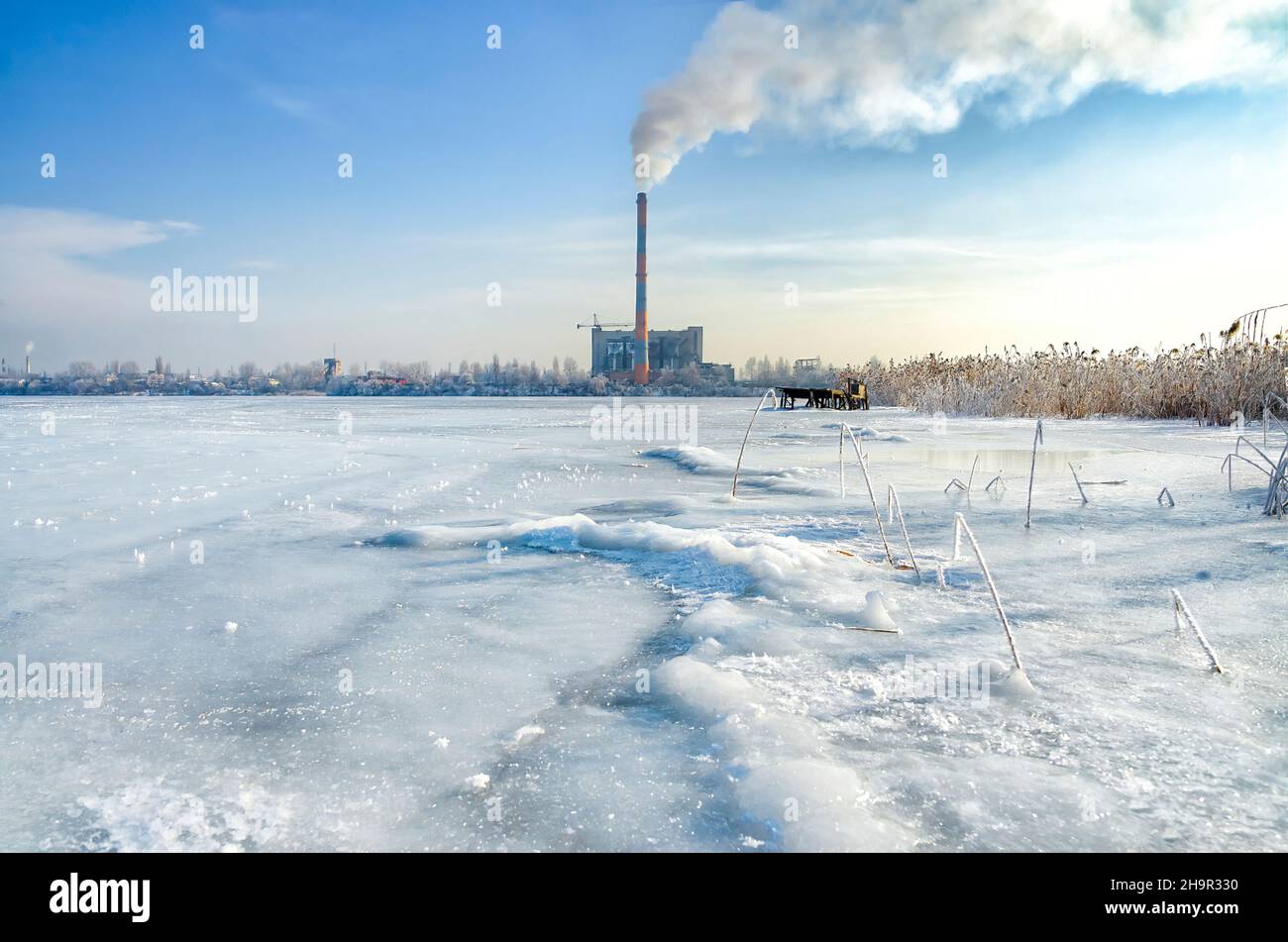 Vue de la cheminée à fumée de l'usine d'incinération des déchets de l'étang gelé.Pollution produite par la combustion des ordures. Banque D'Images