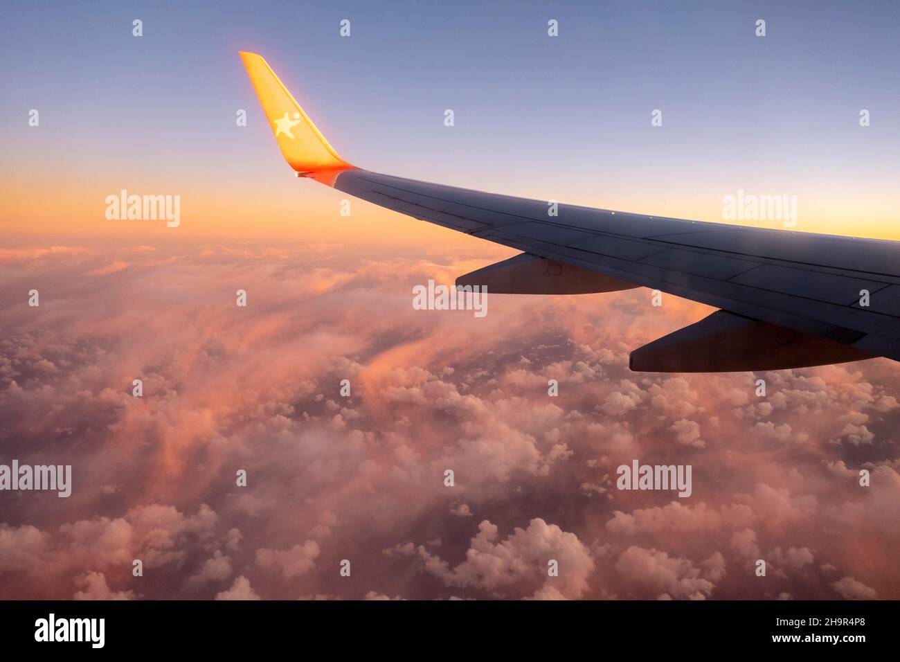 Aile de l'avion, vol au-dessus de la couverture nuageuse, coucher de soleil Banque D'Images