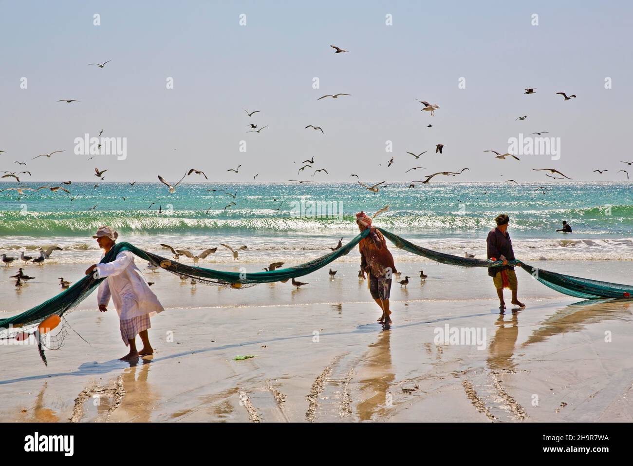 Pêcheurs transportant des filets sur la plage, Salalah, Salalah, Dhofar, Oman Banque D'Images