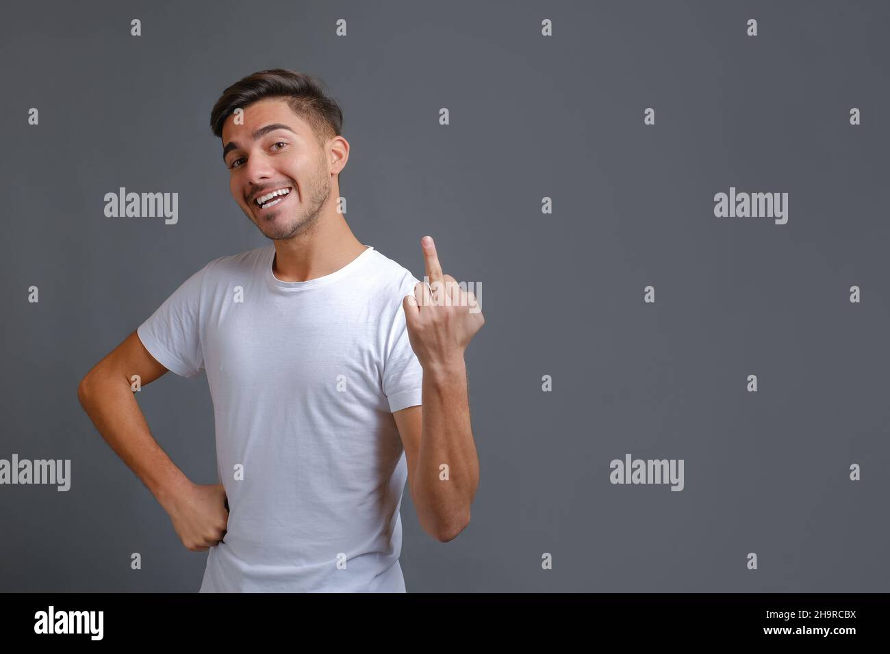 Gars portant un t-shirt blanc debout et montrant le doigt du milieu Banque D'Images