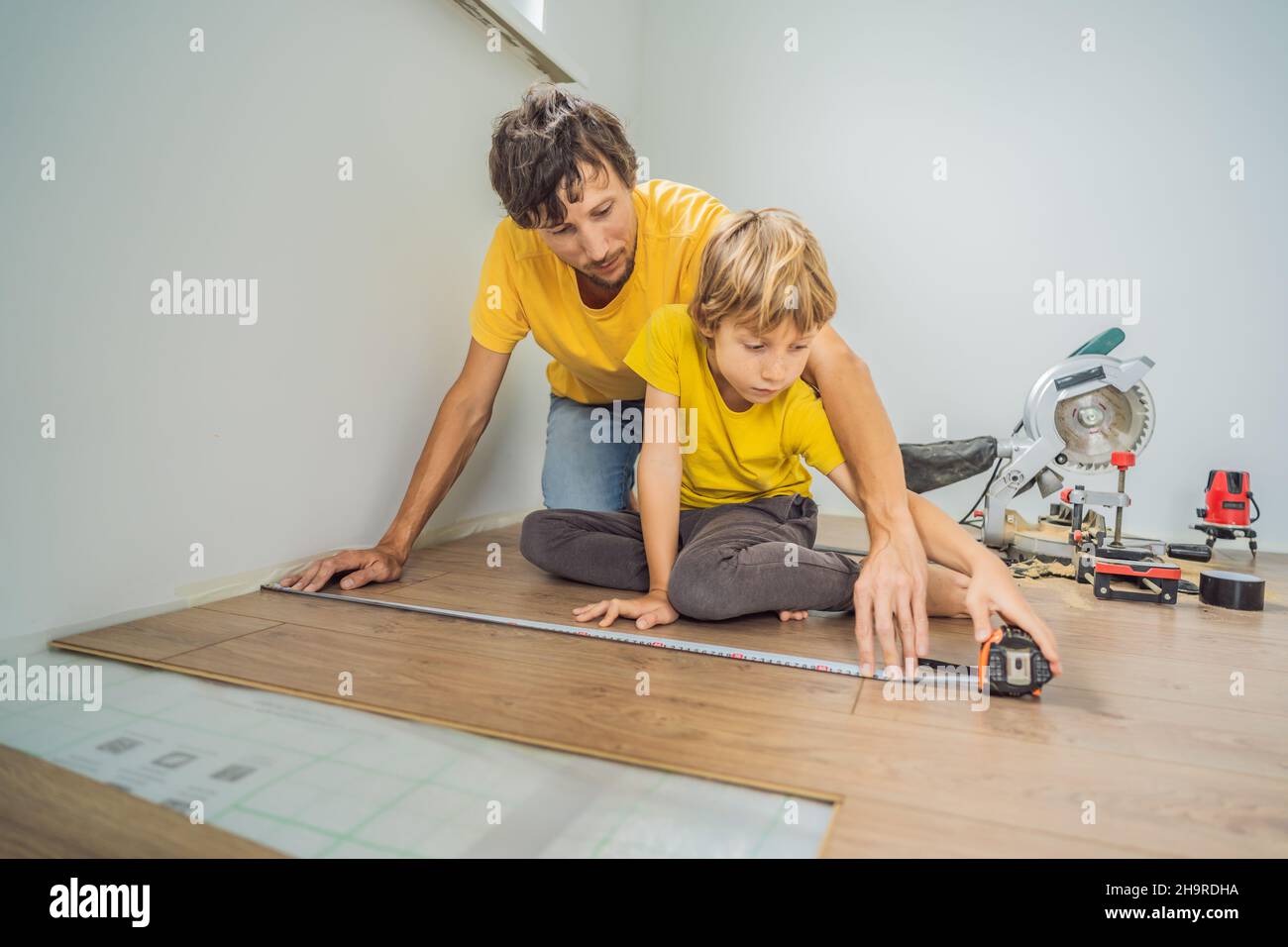 Père et fils installant un nouveau parquet stratifié en bois sur un — free download