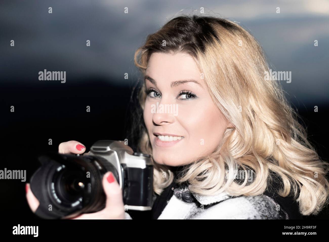 photographe blond souriant en regardant l'appareil photo Banque D'Images