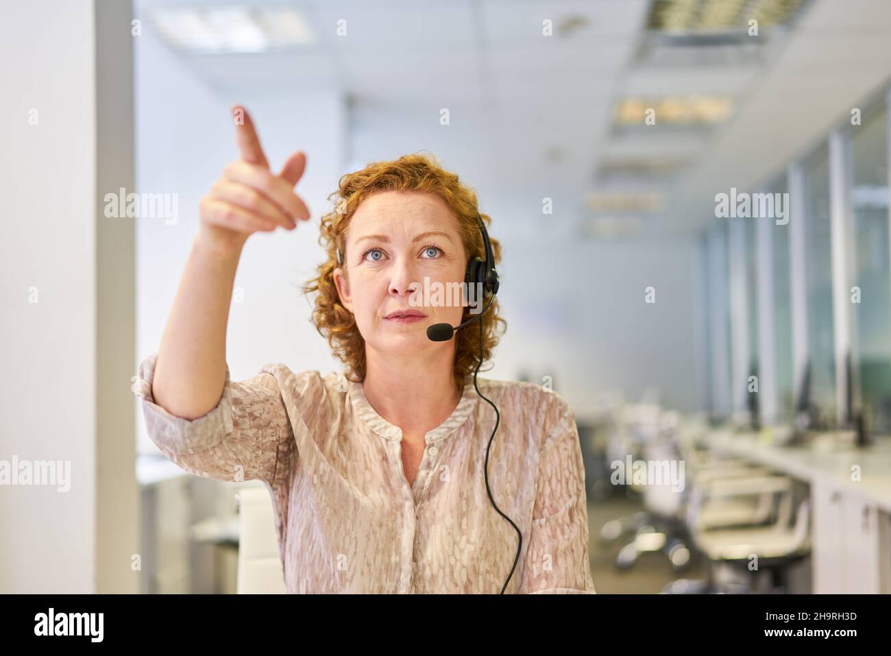 Femme d'affaires avec micro-casque dans le centre d'appels en tant que conseiller client ou en vidéoconférence Banque D'Images