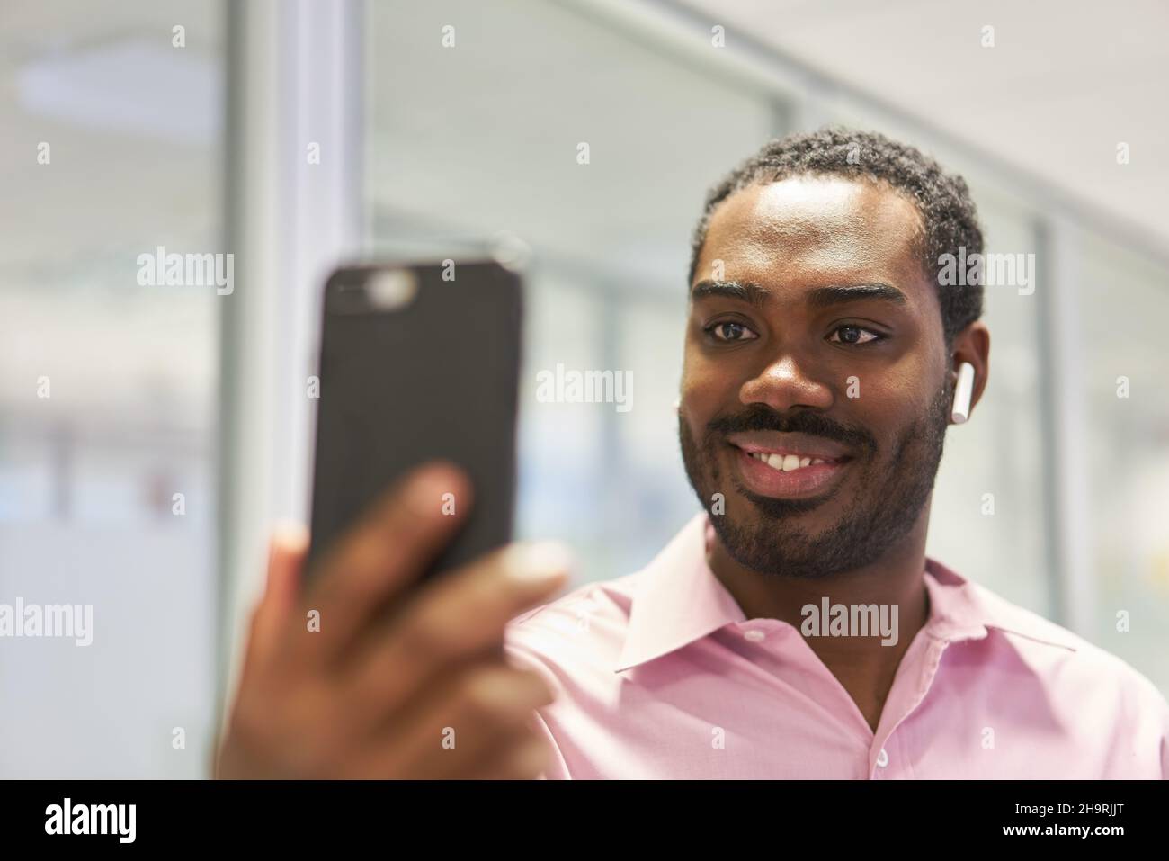 Chat vidéo de jeunes hommes d'affaires avec un smartphone et un casque bluetooth Banque D'Images