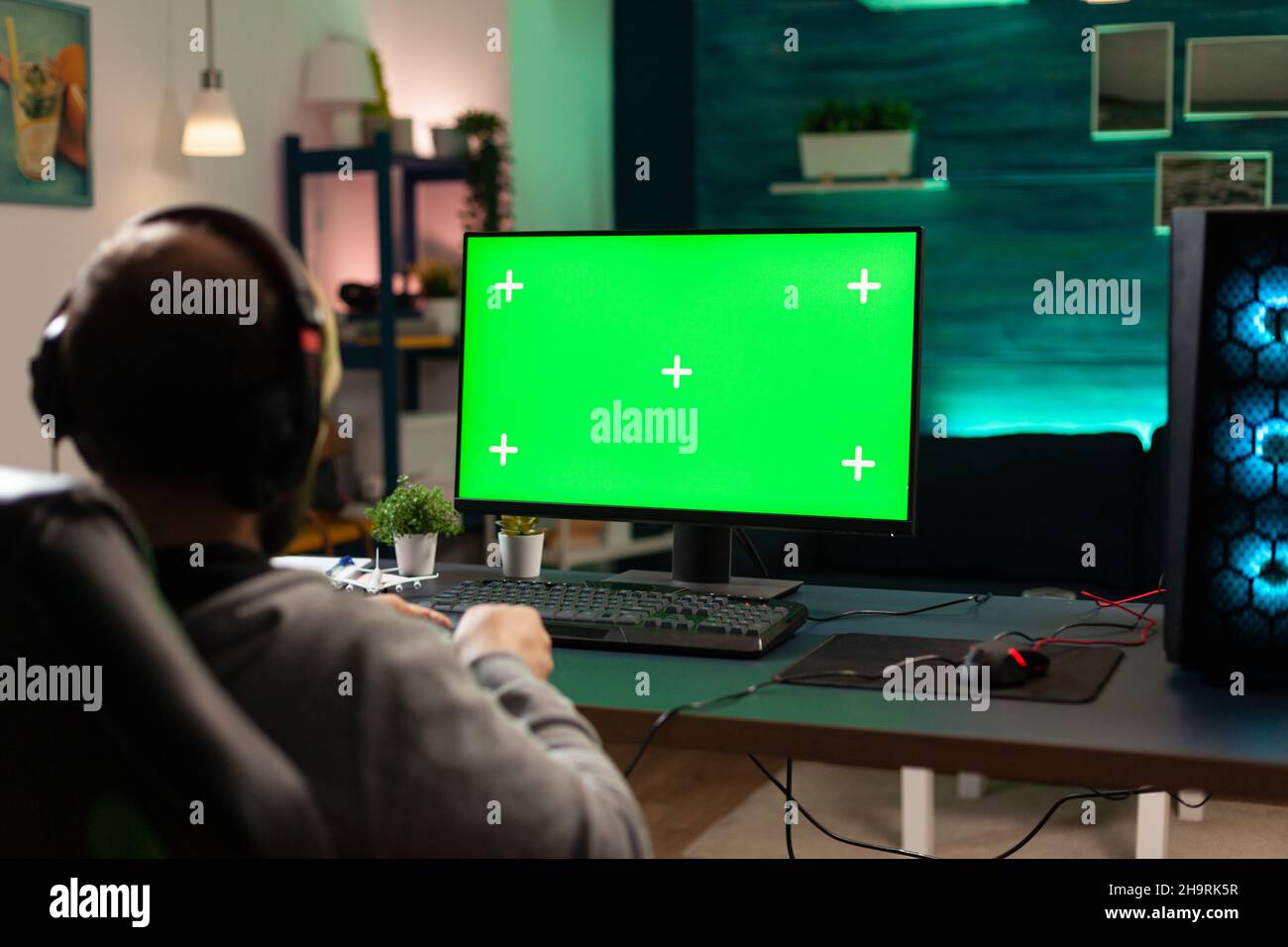 Lecteur regardant l'ordinateur avec écran vert horizontal.Homme utilisant un modèle isolé et un fond de maquette avec la touche chroma pour jouer à des jeux vidéo sur le moniteur.Manette de maintien du joueur. Banque D'Images