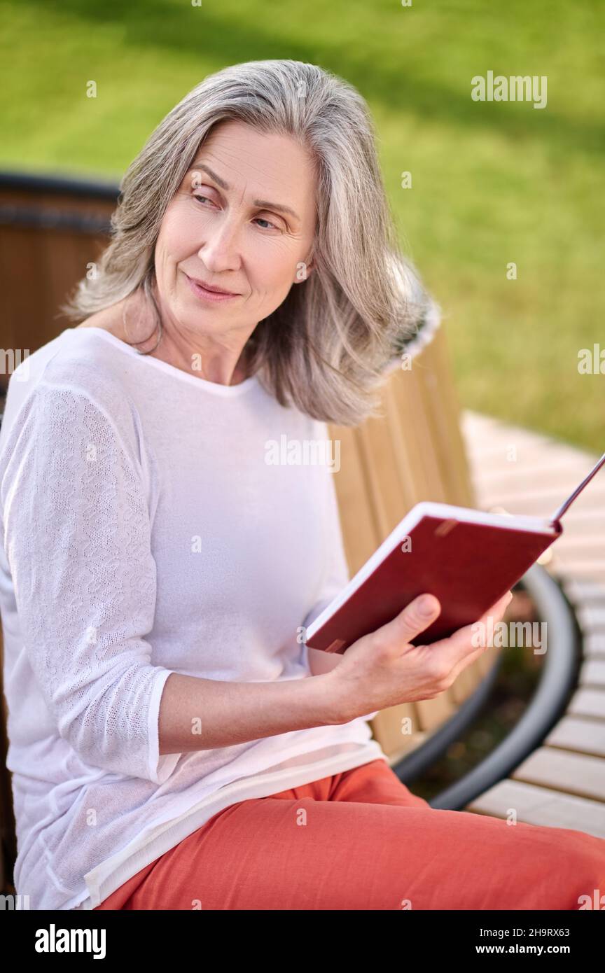 Femme méditative avec livre assis sur le banc Banque D'Images