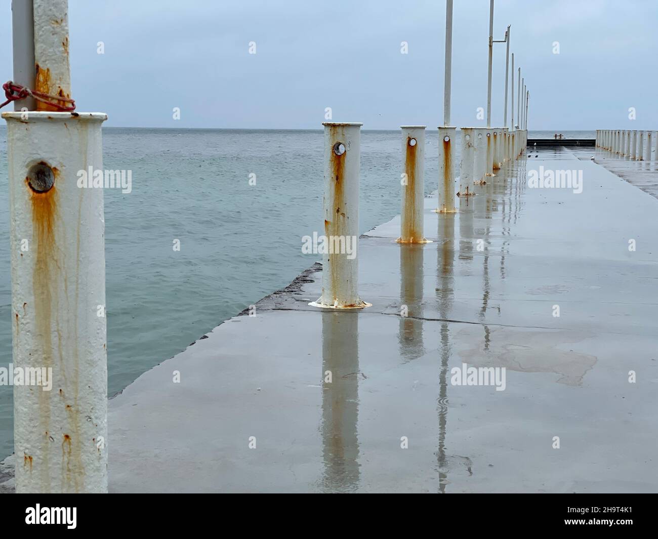 Jetée en béton humide dans la mer par temps pluvieux Banque D'Images