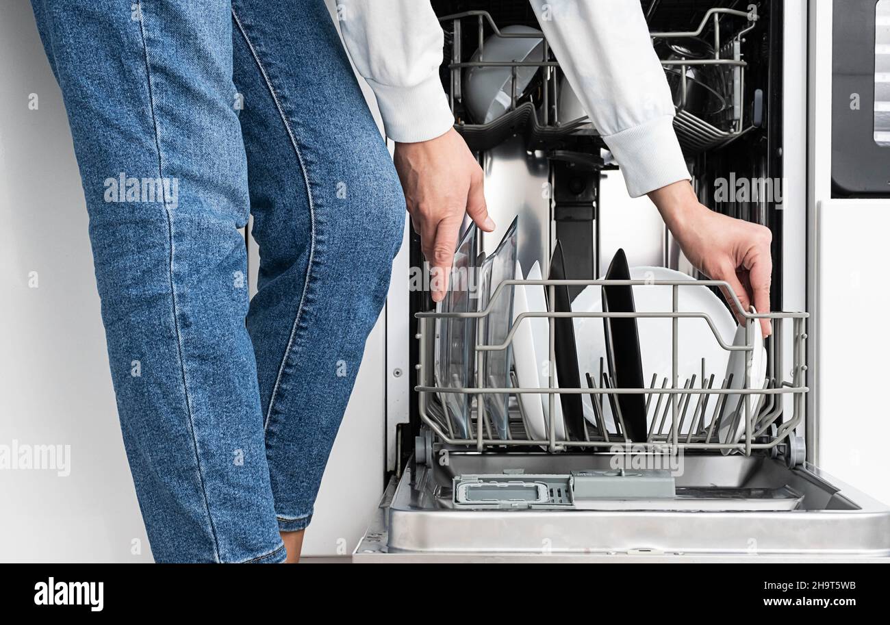 Femme faisant de la vaisselle au lave-vaisselle à la maison. Nettoyez les assiettes après avoir lavé la cuisine moderne avec lave-vaisselle. Tâches ménagères. Banque D'Images