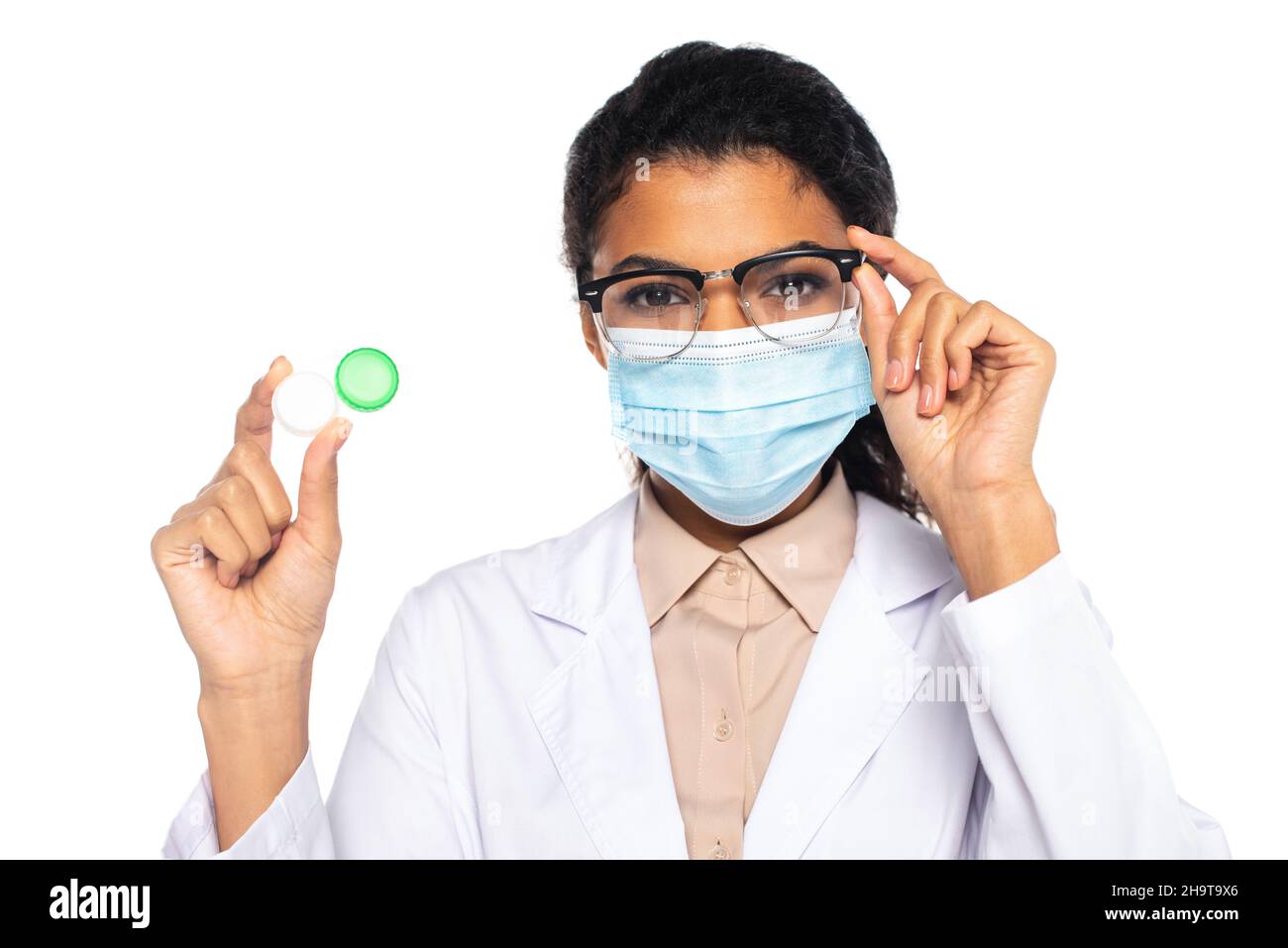 Afro-américain médecin en lunettes et masque médical tenant un contenant avec des lentilles isolées sur blanc Banque D'Images