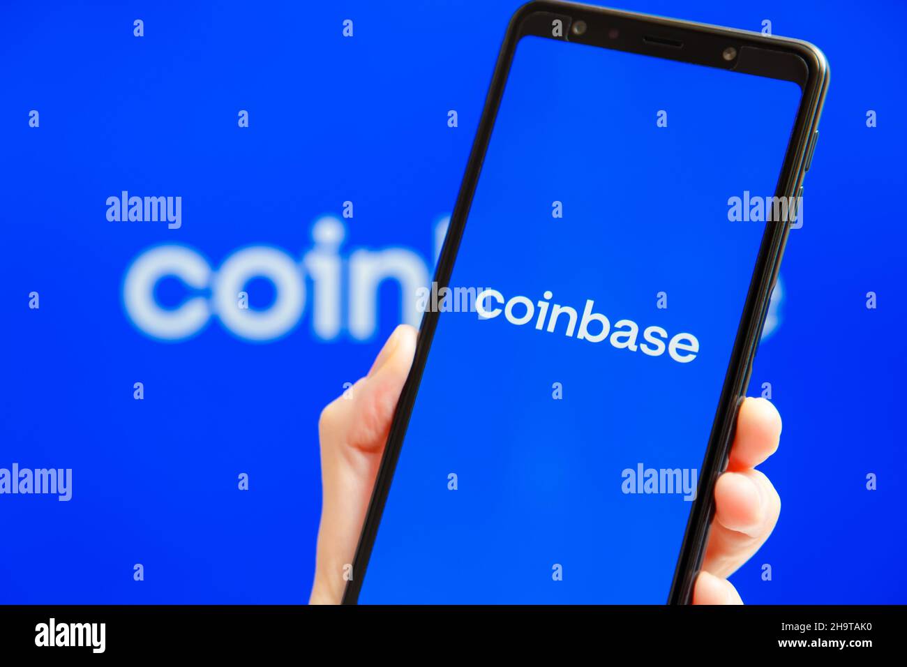 Ukraine, Odessa - octobre, 9 2021: Main tenant mobile avec l'application Coinbase tournant sur l'écran de smartphone avec le logo Coinbase en arrière-plan.Coinbase - plate-forme américaine d'échange et de négociation de crypto-monnaies Banque D'Images