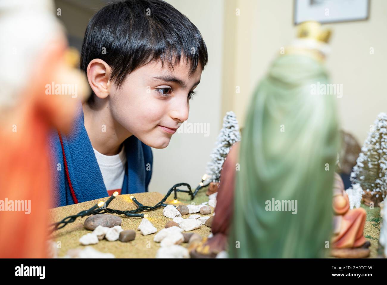Un garçon de six ans regarde la scène de la crèche de Noël Banque D'Images