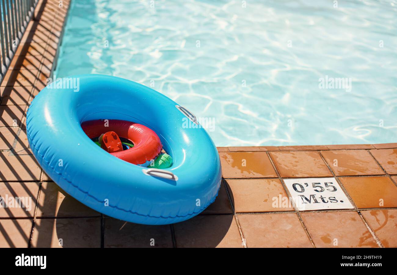 Roue gonflable bleu vif et jouets aquatiques à côté de la piscine