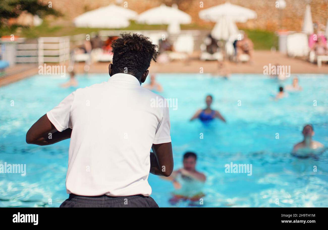 Black Athletic hôtel station animator s'entraîner devant la piscine, voir la forme derrière les gens flou arrière-plan - l'activité aérobie de l'eau Banque D'Images