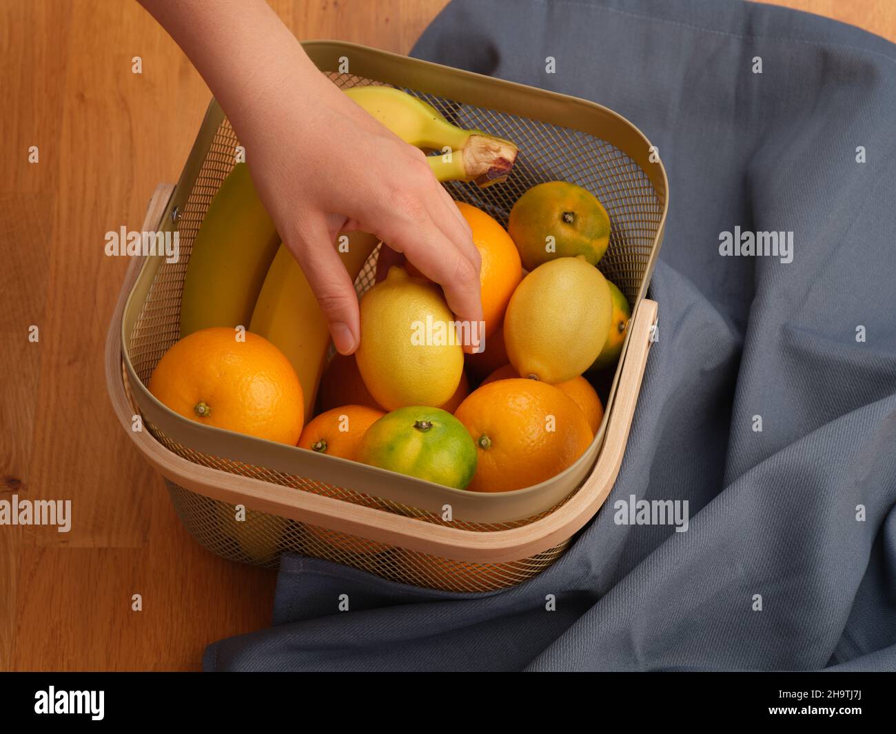 Une femme mettant sa main dans un panier de fruits et tirant un citron.Gros plan. Banque D'Images