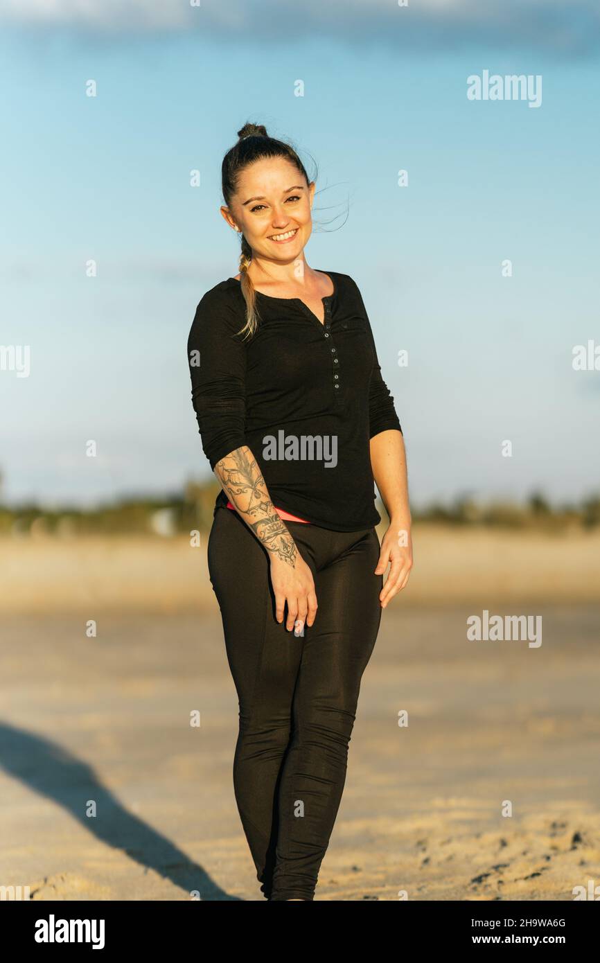 Portrait vertical d'une femme blonde en vêtements de sport face à l'appareil photo sur une plage Banque D'Images