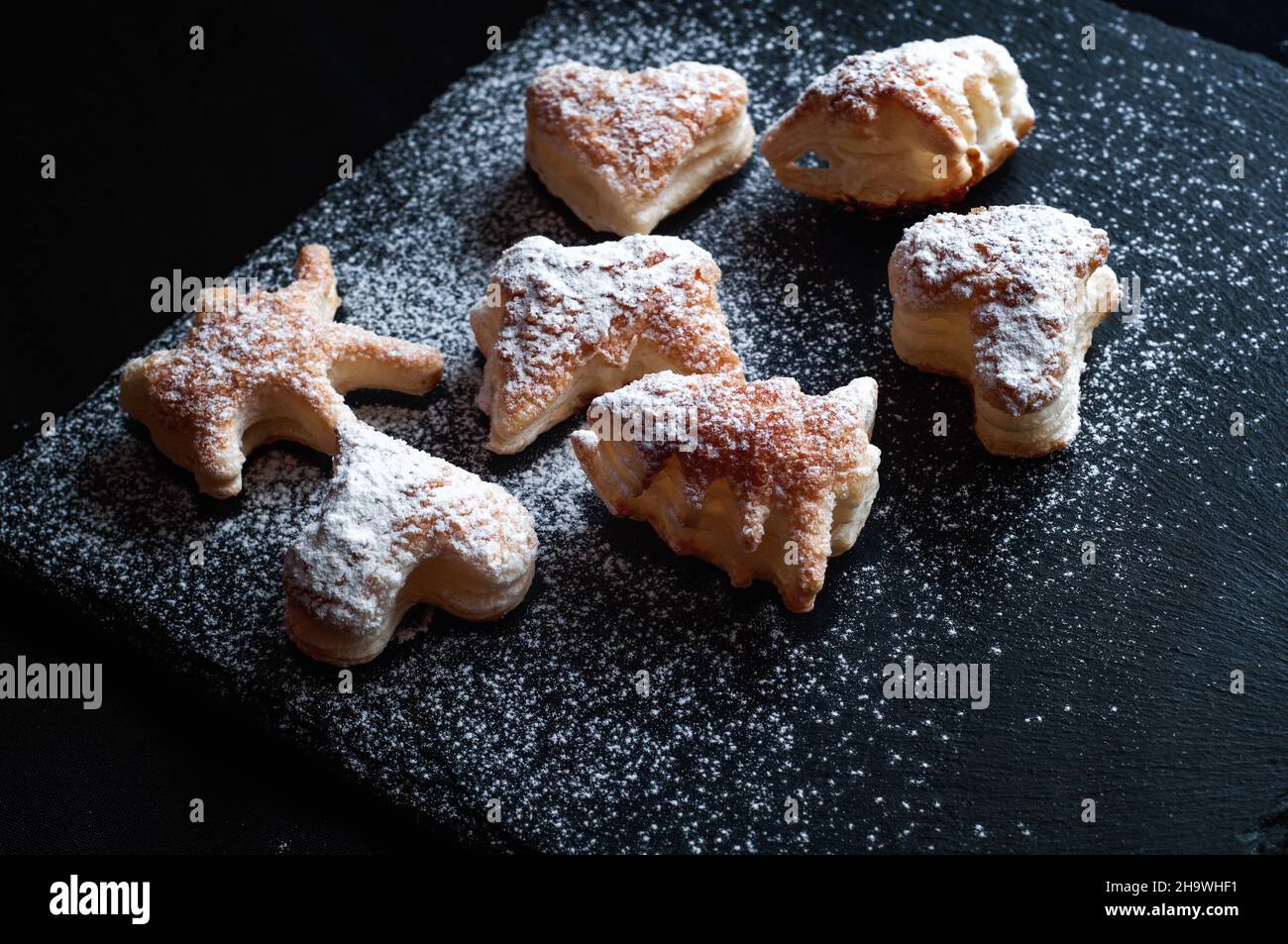 savoureux fond de gâteaux à la cannelle de pâte feuilletée sur fond d'ardoise noire, saupoudrés de sucre en poudre Banque D'Images