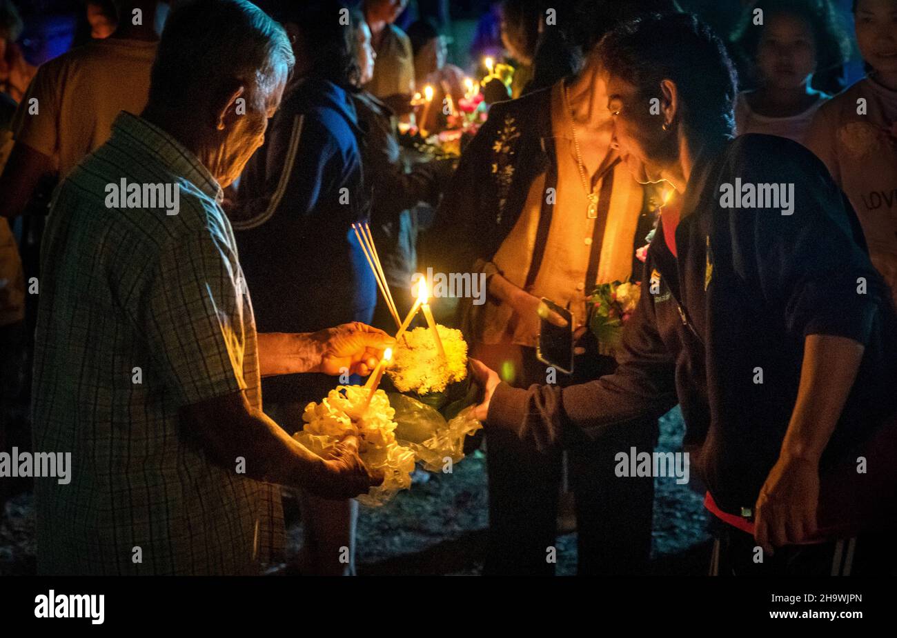 Éclairant des bougies pour flotter sur la rivière lors d'un festival de Loy Krathong en Thaïlande rurale Banque D'Images