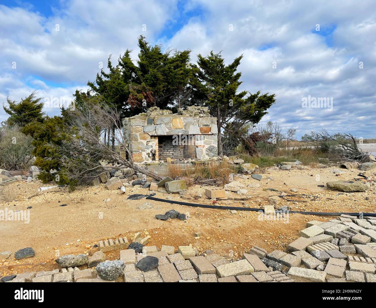 Une cheminée en pierre et en briques du milieu du siècle se trouve dans le sable sur une plage reculée entourée d'arbres, de broussailles et des décombres d'un ouragan dem de longue date Banque D'Images