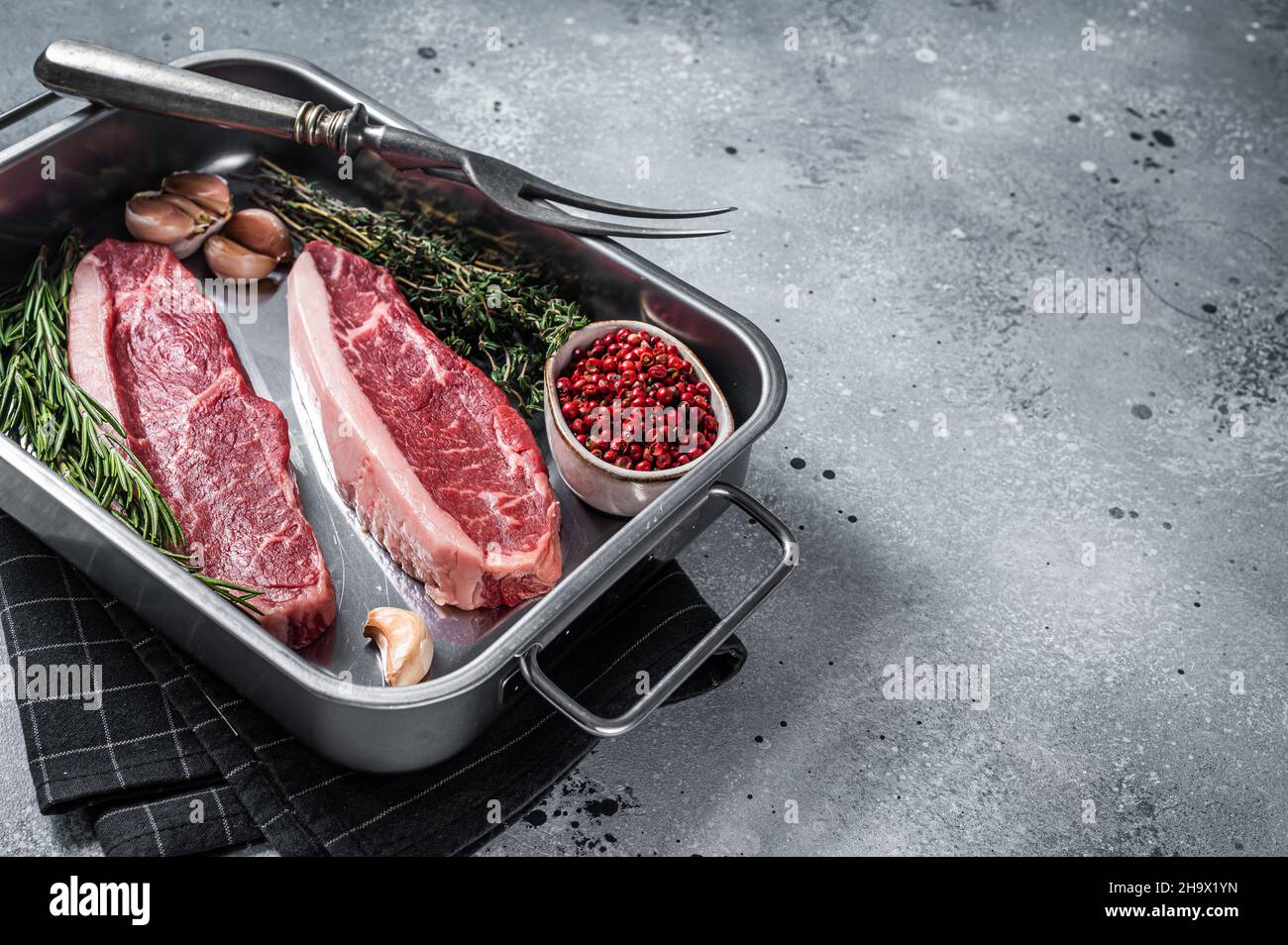 Bœuf de bœuf haché cru ou steak de bœuf de bœuf haché dans le plateau avec des herbes.Arrière-plan gris.Vue de dessus.Copier l'espace Banque D'Images