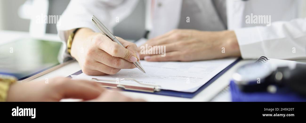 Le médecin écrit des informations dans des documents devant le patient à la fermeture de la clinique Banque D'Images