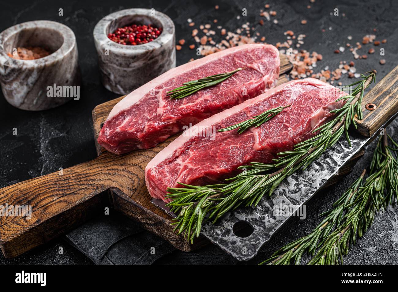 Steak de viande de bœuf de boucherie ou sirloin sur le dessus du butcher.Arrière-plan noir.Vue de dessus Banque D'Images