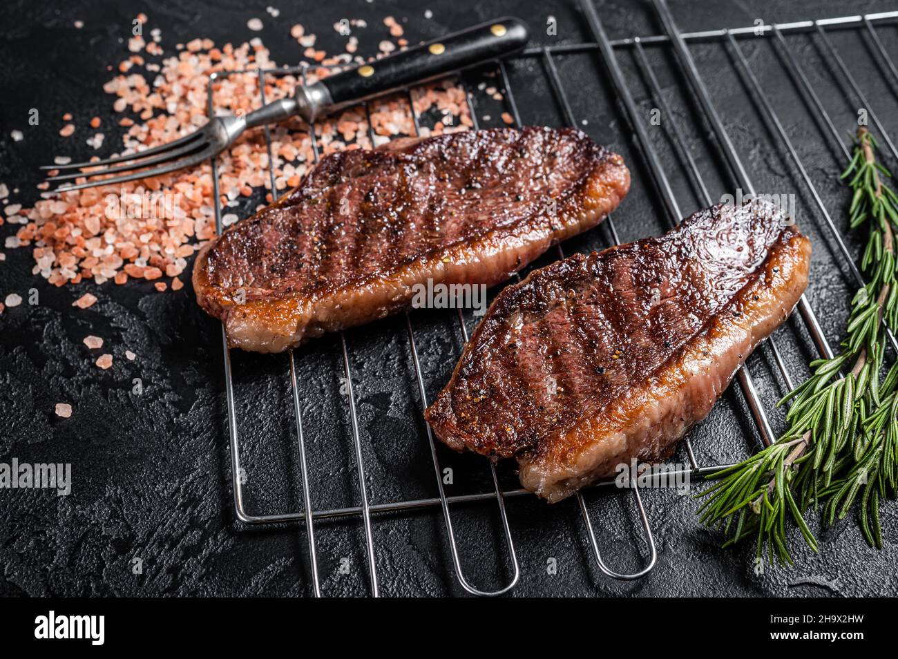 Rôti de chapeau grillé au barbecue ou bifteck de bœuf au sirloin du haut, viande frite sur le gril.Arrière-plan noir.Vue de dessus Banque D'Images