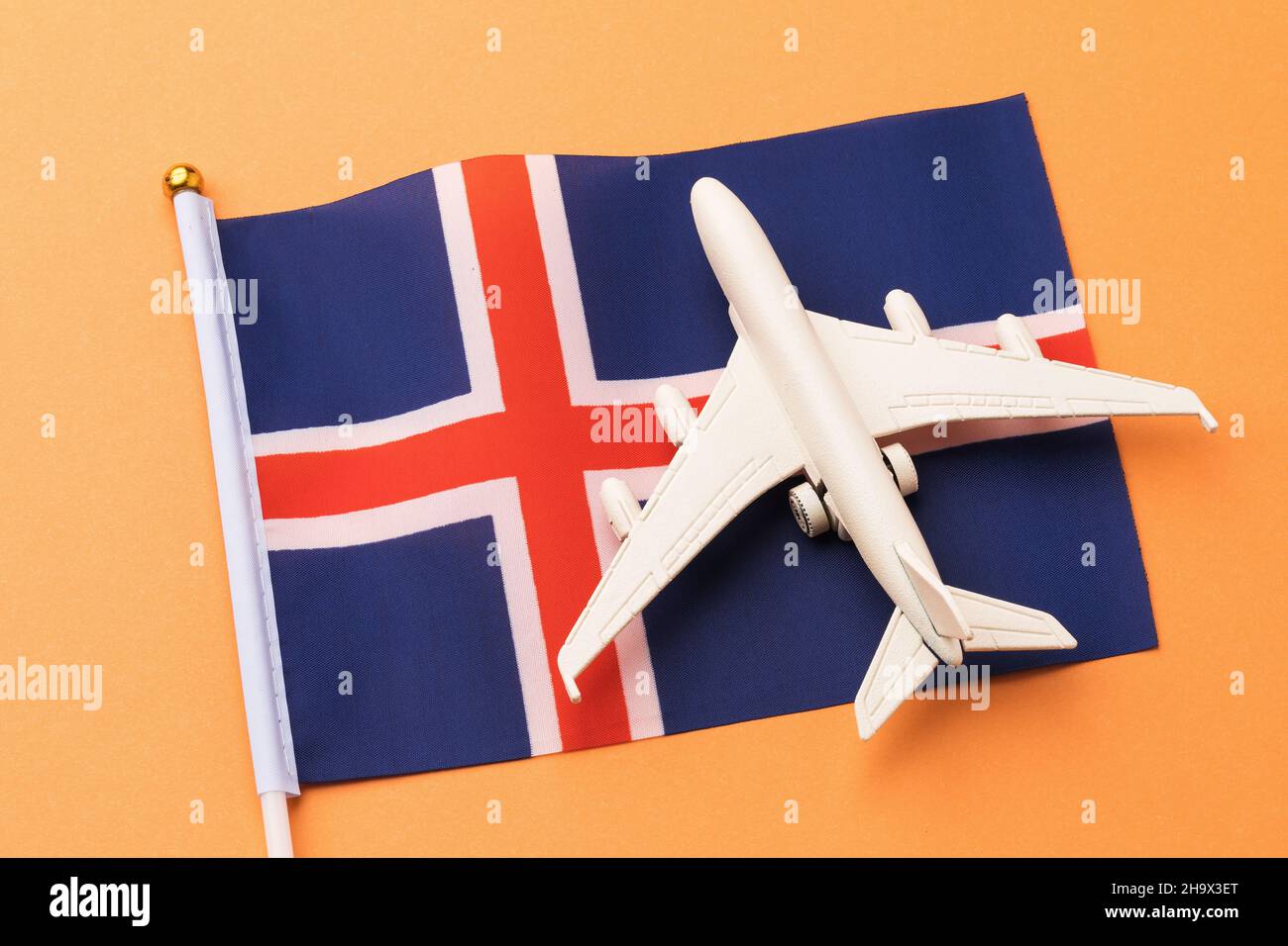 Drapeau de l'Islande et avion jouet sur fond orange, concept de vol vers l'Islande, vue de dessus Banque D'Images