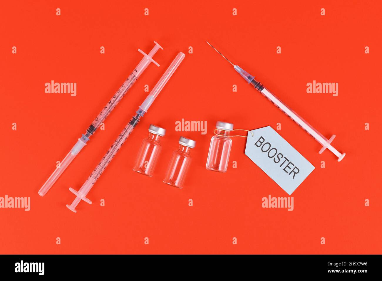 Concept de vaccination de rappel du virus Corina avec flacons et seringues sur fond rouge Banque D'Images