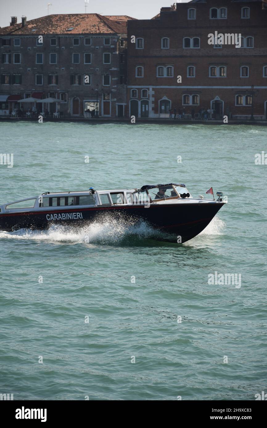 Un bateau de police en Italie rougit le long de la rivière avec des vagues, en arrière-plan deux bâtiments anciens Banque D'Images