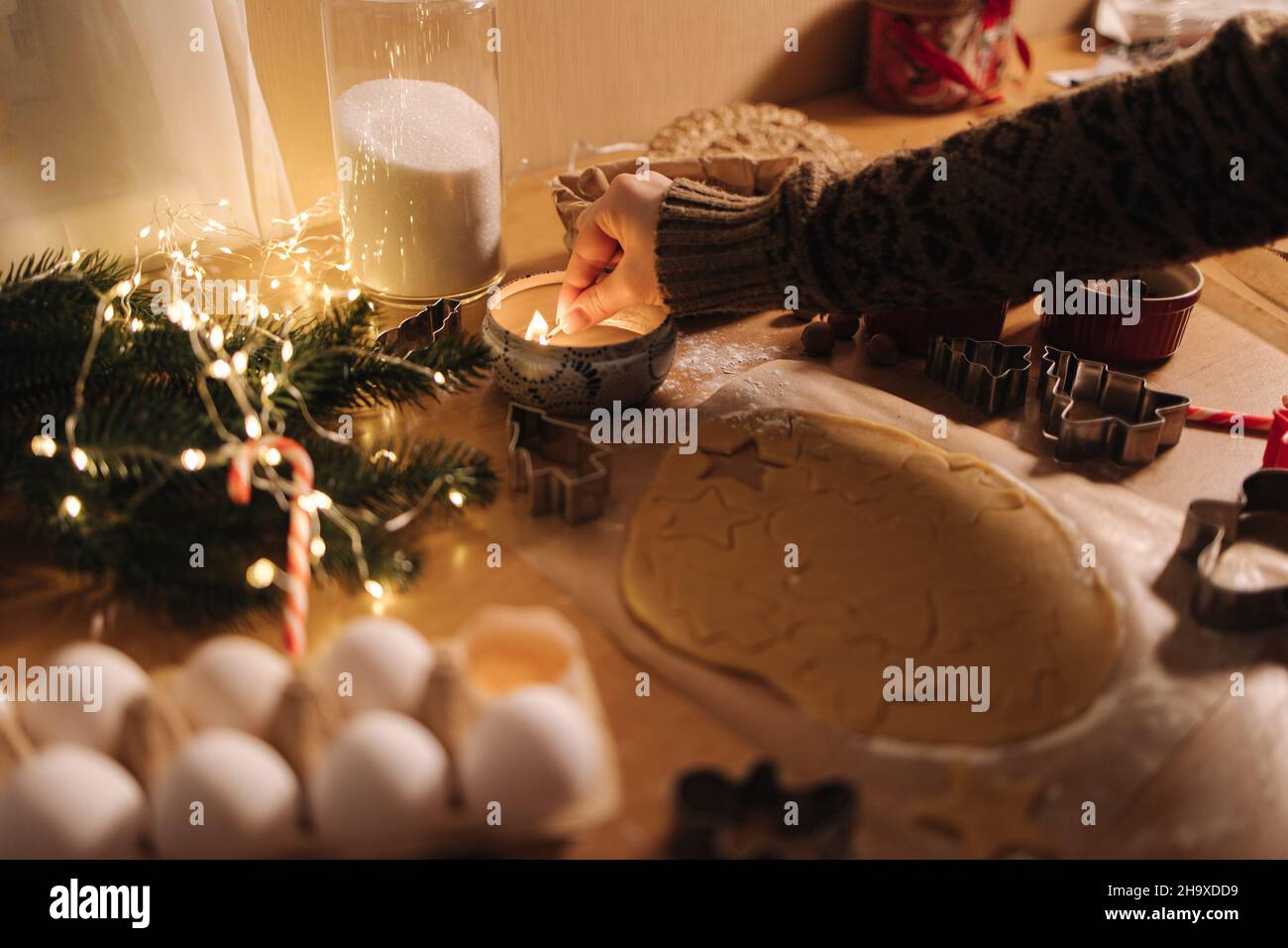 Une femme allume une bougie à Noël.Préparation de la cuisson du pain d'épice.Ambiance de Noël Banque D'Images