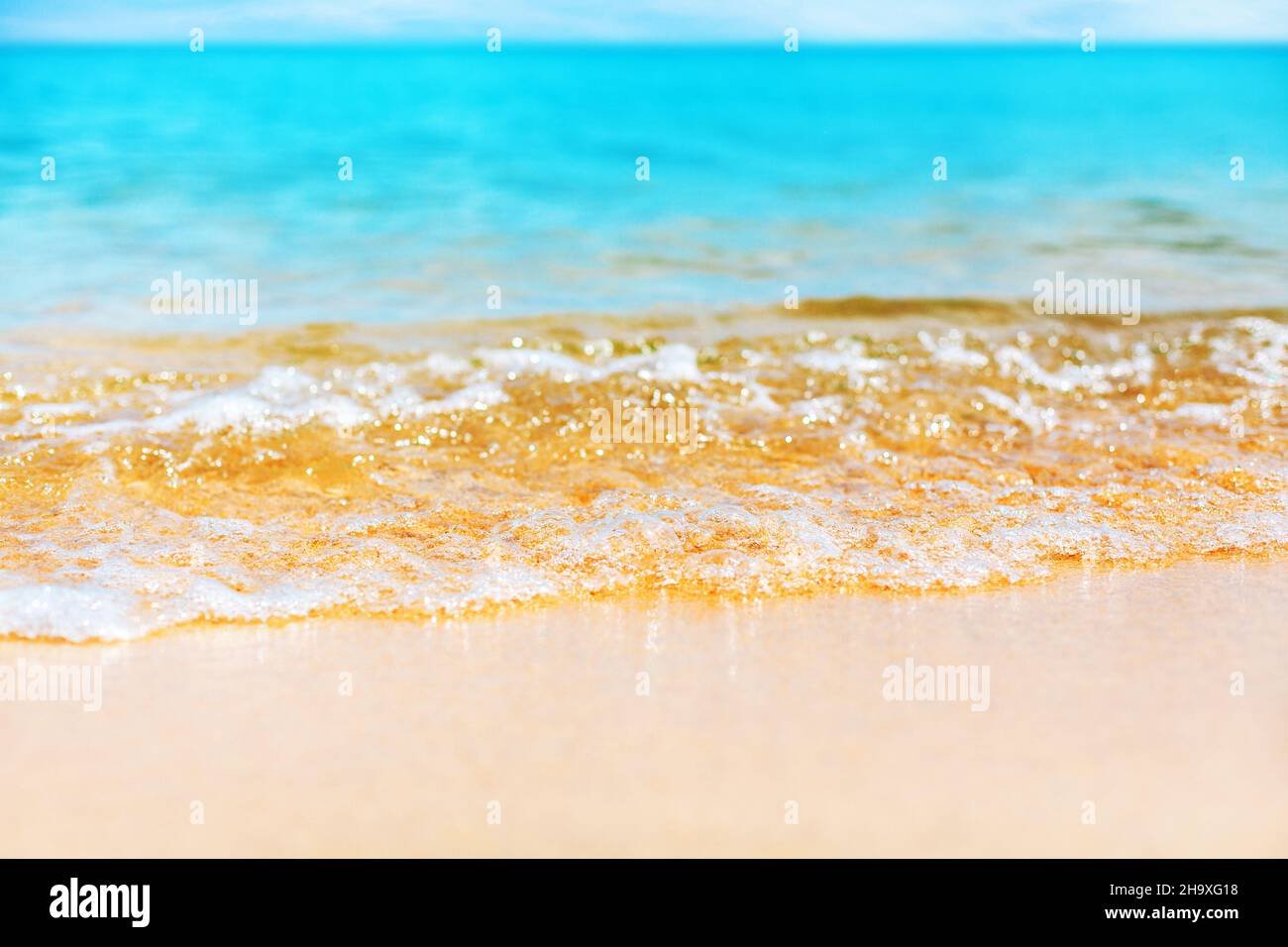 Gros plan sur les vagues bleues, marée marine, eau turquoise, mousse blanche, sable jaune doré,plage tropicale ensoleillée, fond naturel, été Banque D'Images