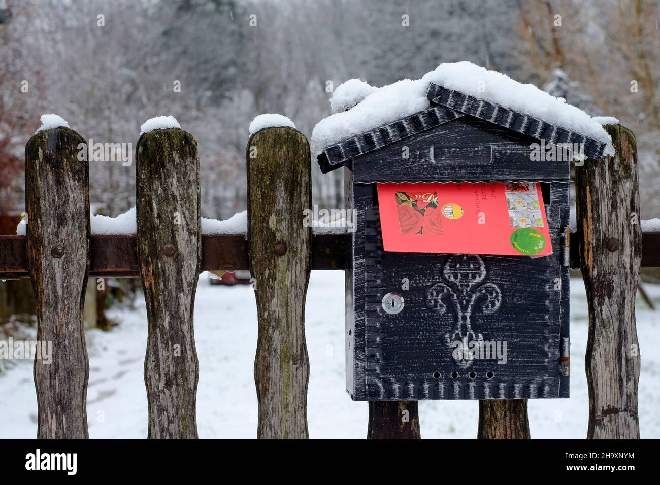 carte de noël dans une enveloppe rouge vif qui dépasse de la boîte aux lettres enneigée montée sur la porte du jardin de la maison du comté de zala hongrie Banque D'Images