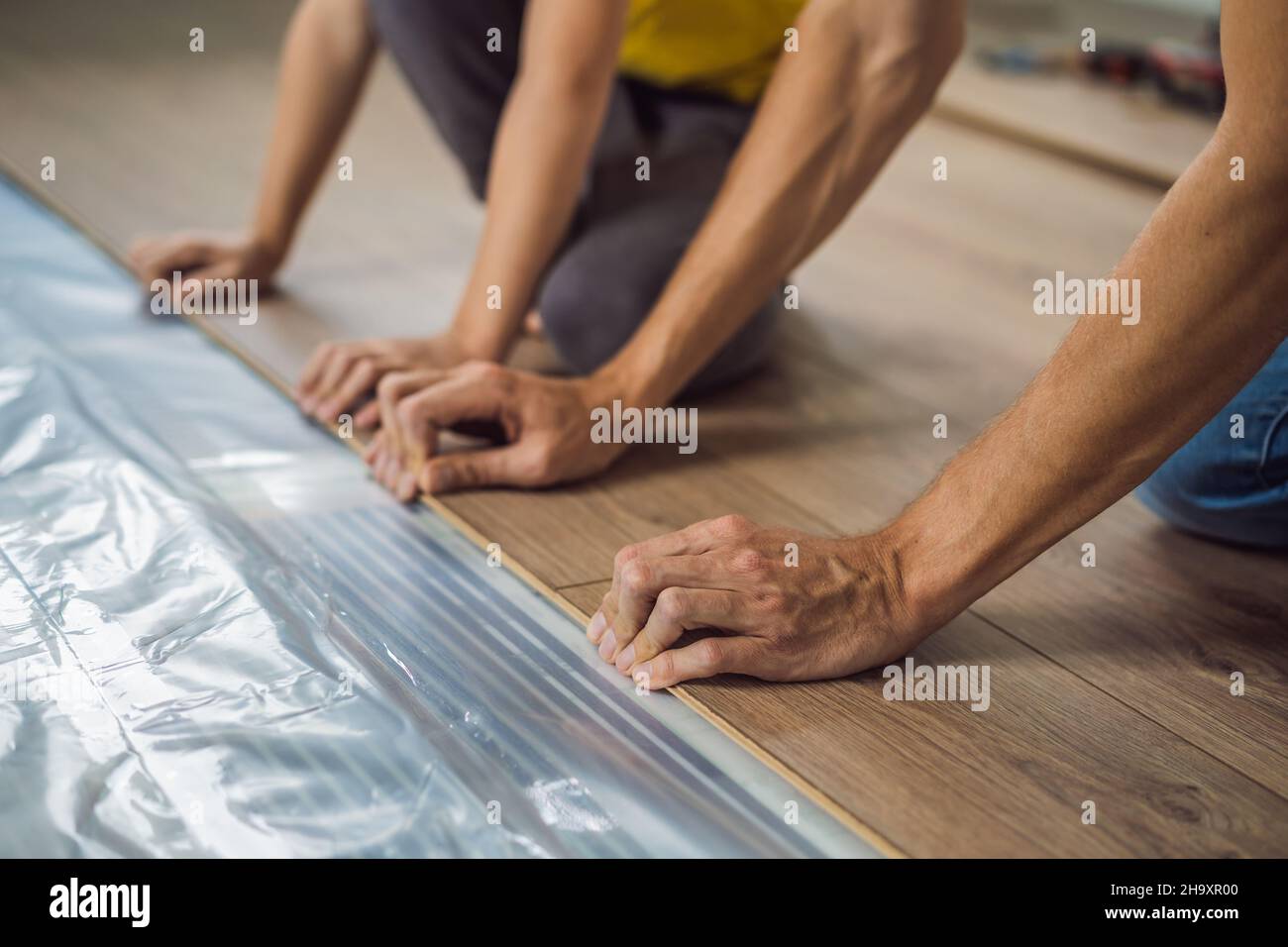 Père et fils installant un nouveau parquet stratifié en bois sur un — free download