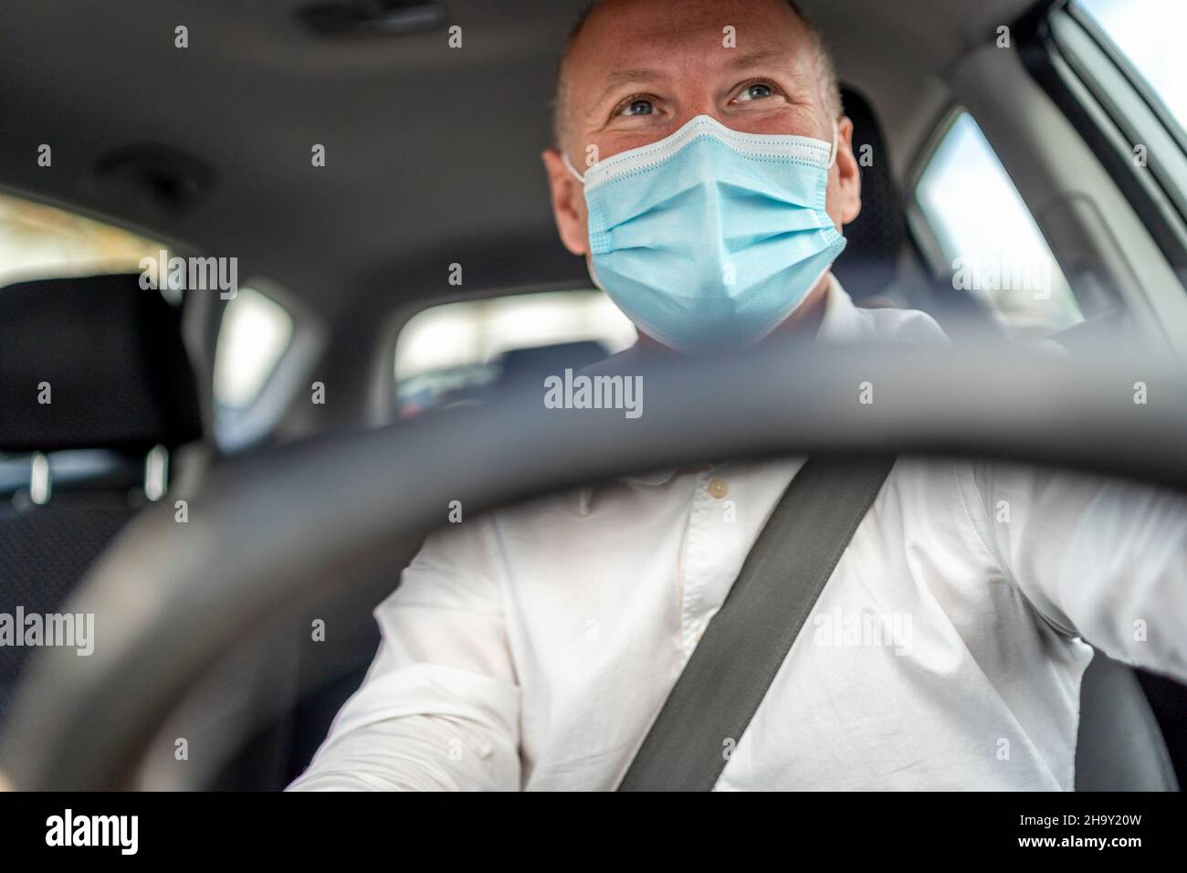 Un homme dans un masque de protection conduisant une voiture, volant au premier plan, Portugal Banque D'Images