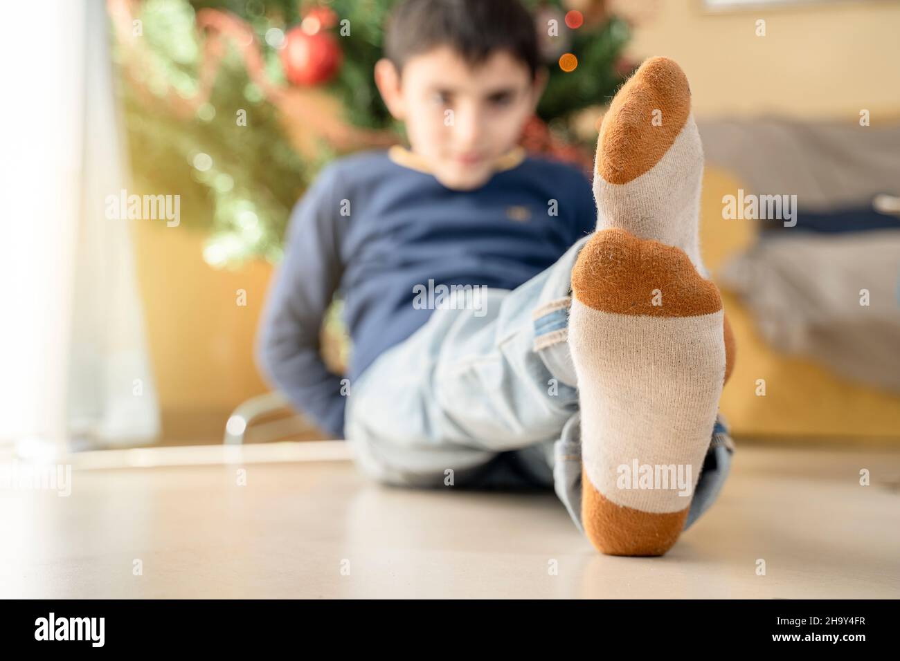 Les enfants se trouvent dans des chaussettes de Noël, allongés au pied de l'arbre de noël, en appréciant le temps de noël Banque D'Images