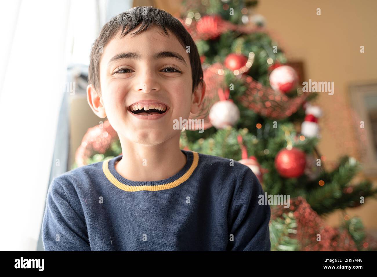 Jeune garçon souriant sur le fond arbre de Noël à la maison. Heureux rire enfant. Amusant enfant. Banque D'Images