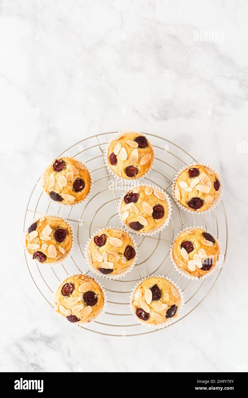 Muffins aux cerises faits maison sur un support de refroidissement sur fond de marbre blanc avec espace de copie.Vue de dessus. Banque D'Images