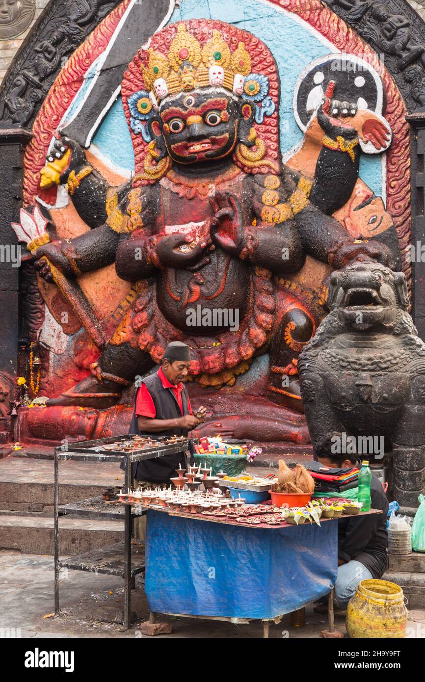 Un vendeur vend des offres au sanctuaire hindou du Kala ou du Bhairab noir à Durbar Square, Kathamandu, Népal.Le Bhairab noir est le destructeur Banque D'Images