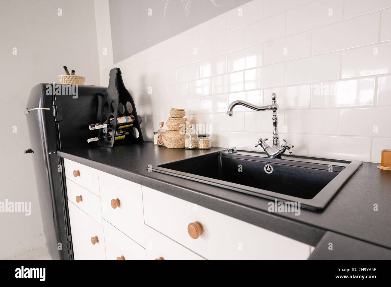 évier noir de style rétro avec robinet pour l'eau dans une cuisine légère, meubles de cuisine, comptoir en marbre noir, armoire de cuisine, carreaux blancs sur le mur.Photo de haute qualité Banque D'Images