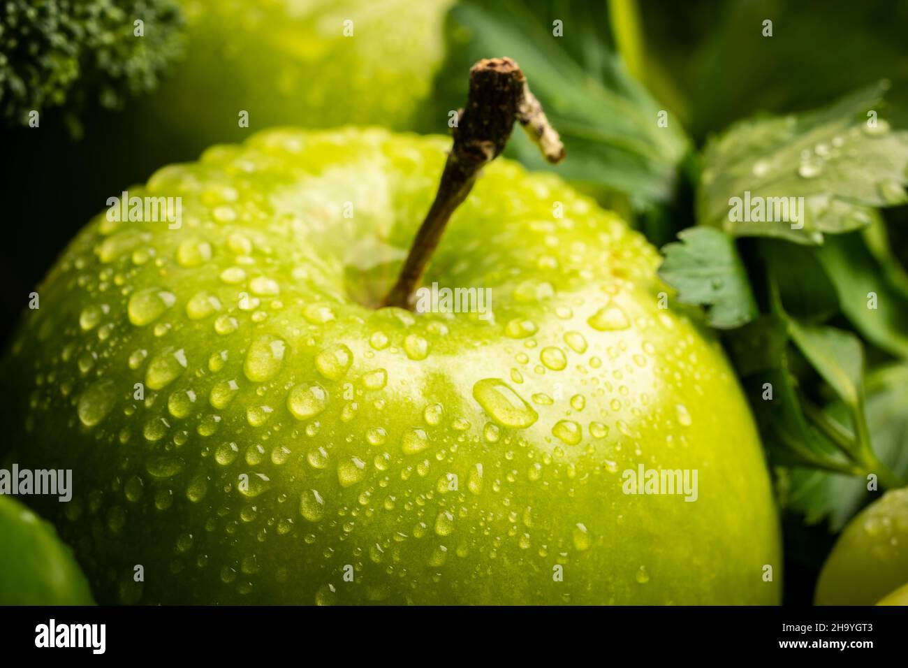 Pomme verte mûre fraîche recouverte de gouttes d'eau. Banque D'Images