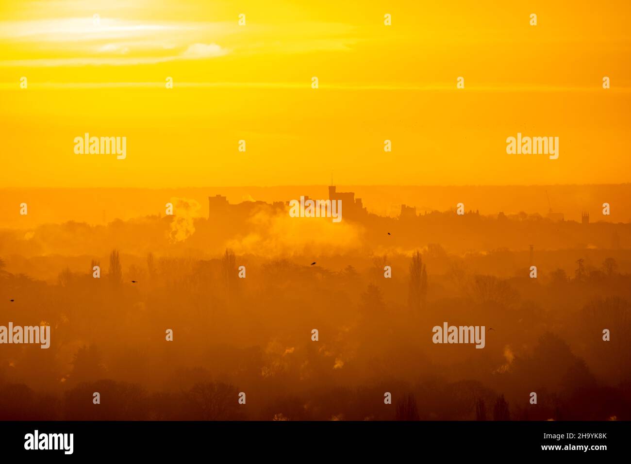 Lever du soleil en hiver avec le château de Windsor émergeant de la brume à l'horizon Banque D'Images