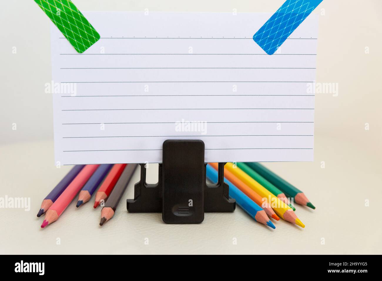 Accessoires d'école sur une table blanche, feuille de papier et crayons. Banque D'Images